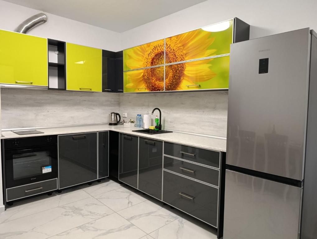 a kitchen with black cabinets and a sunflower painting on the wall at Vitosha view Mladost apartment in Sofia