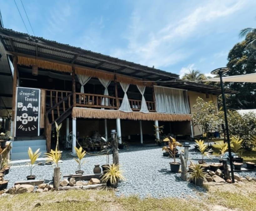 a building with palm trees in front of it at Baan Koody Hostel in Ko Kut