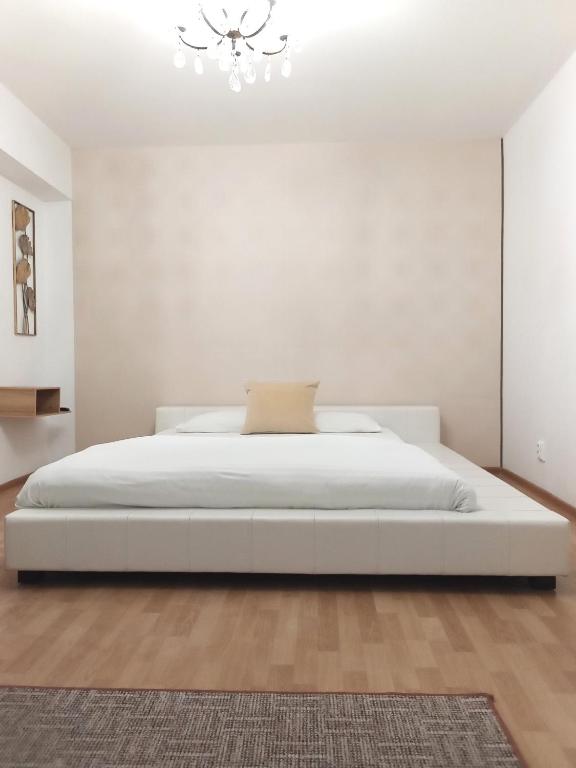 ein weißes Schlafzimmer mit einem weißen Bett und einem Kronleuchter in der Unterkunft Maison 29 in Braşov