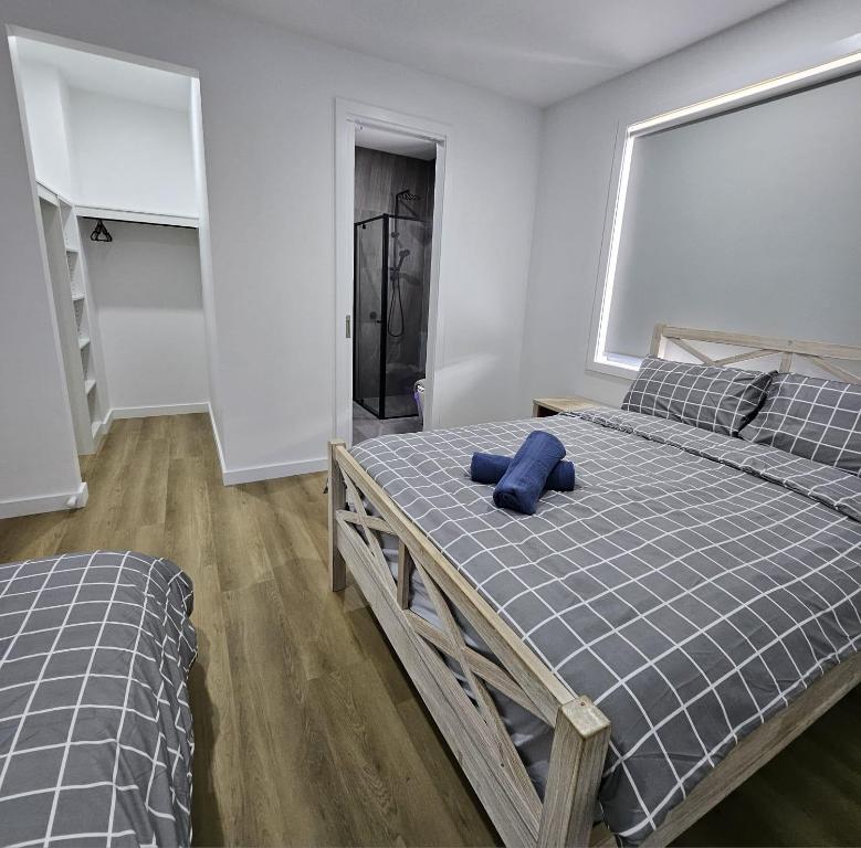 ein Schlafzimmer mit zwei Betten mit einem blauen Kissen darauf in der Unterkunft Maruve Guesthouse Plus- Modern Stay near Melb Airport 12 min in Melbourne