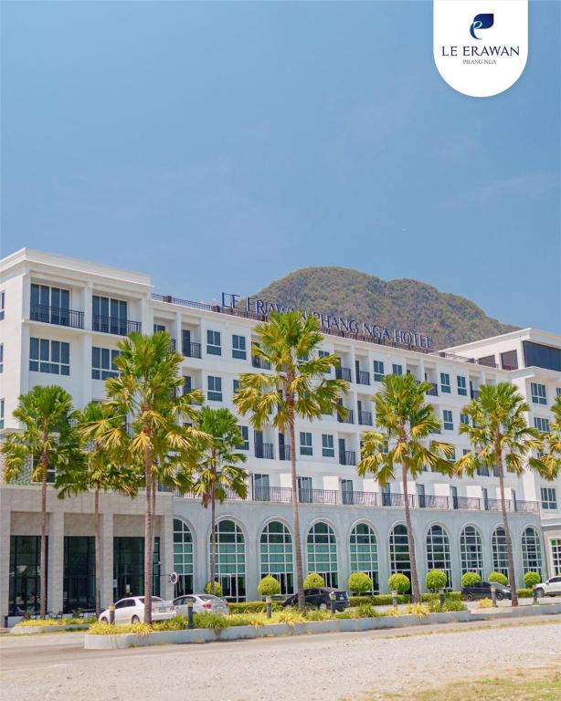 a large white building with palm trees in front of it at Le Erawan Phang Nga Hotel in Phangnga