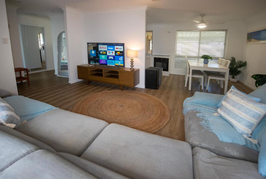 ein Wohnzimmer mit einer Couch, einem Fernseher und einem Tisch in der Unterkunft Serene Saltair in Redland Bay