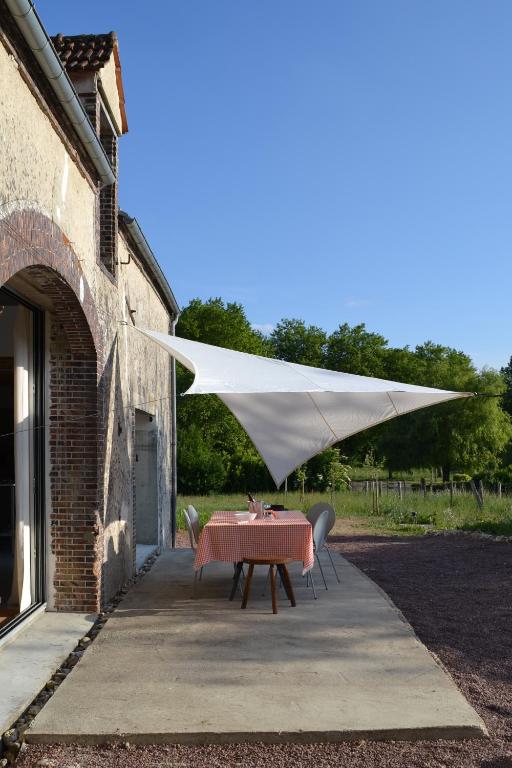 a table and chairs under a white umbrella at Grange habitée, nature & design in Manou
