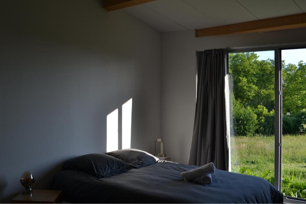 ein Schlafzimmer mit einem Bett und einem großen Fenster in der Unterkunft Grange habitée, nature & design in Manou