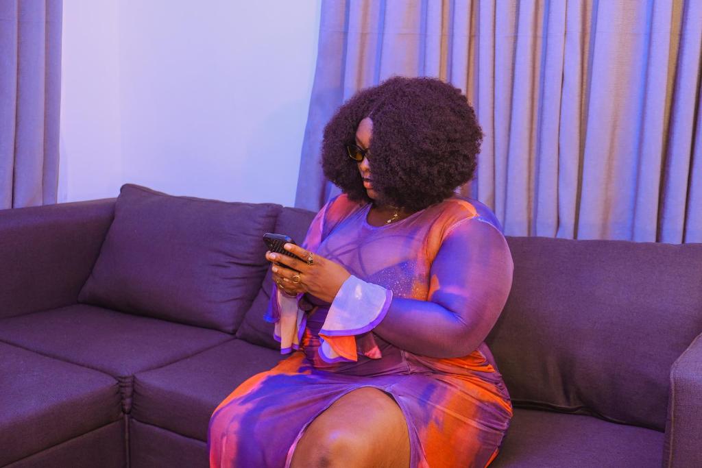 イバダンにあるLOJ Homesのソファに座って携帯電話を見ている女性