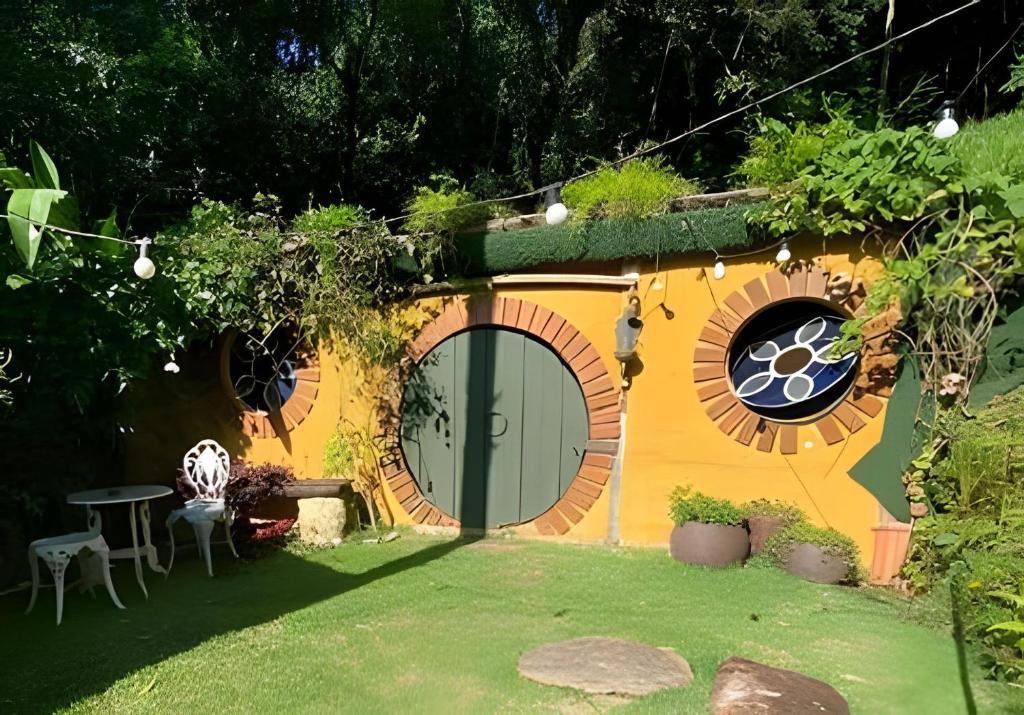 a small house with a circular window and a table at Casa dos Hobbits: Lago, cascata, caiaque, piscina in Itatiba
