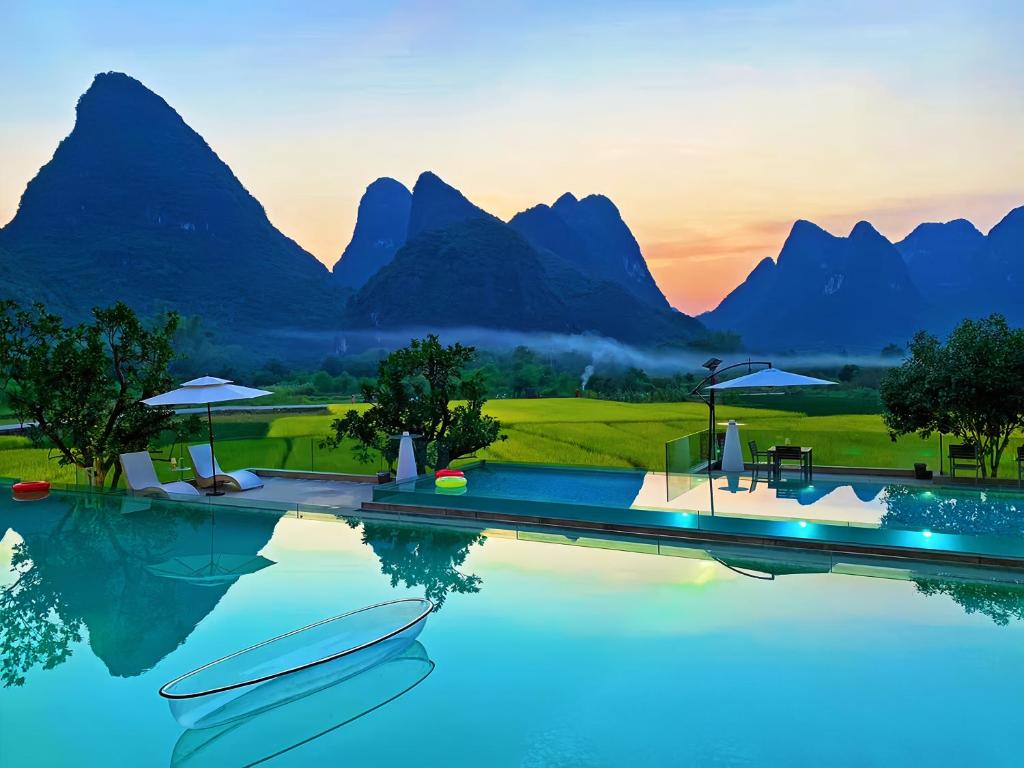 ein Resortpool mit Bergen im Hintergrund in der Unterkunft Yangshuo County Rice Field Resort Hotel in Yangshuo