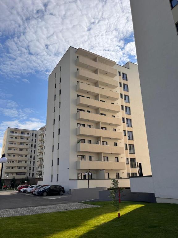 a large white building with cars parked in a parking lot at AV Urban Retreat in Ploieşti