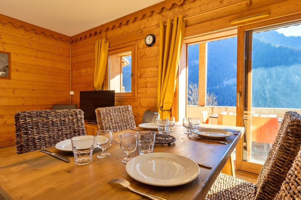 尚帕尼恩瓦努瓦茲Pralioud – Confort moderne, spa & piscine的用餐室配有带盘子和玻璃杯的桌子