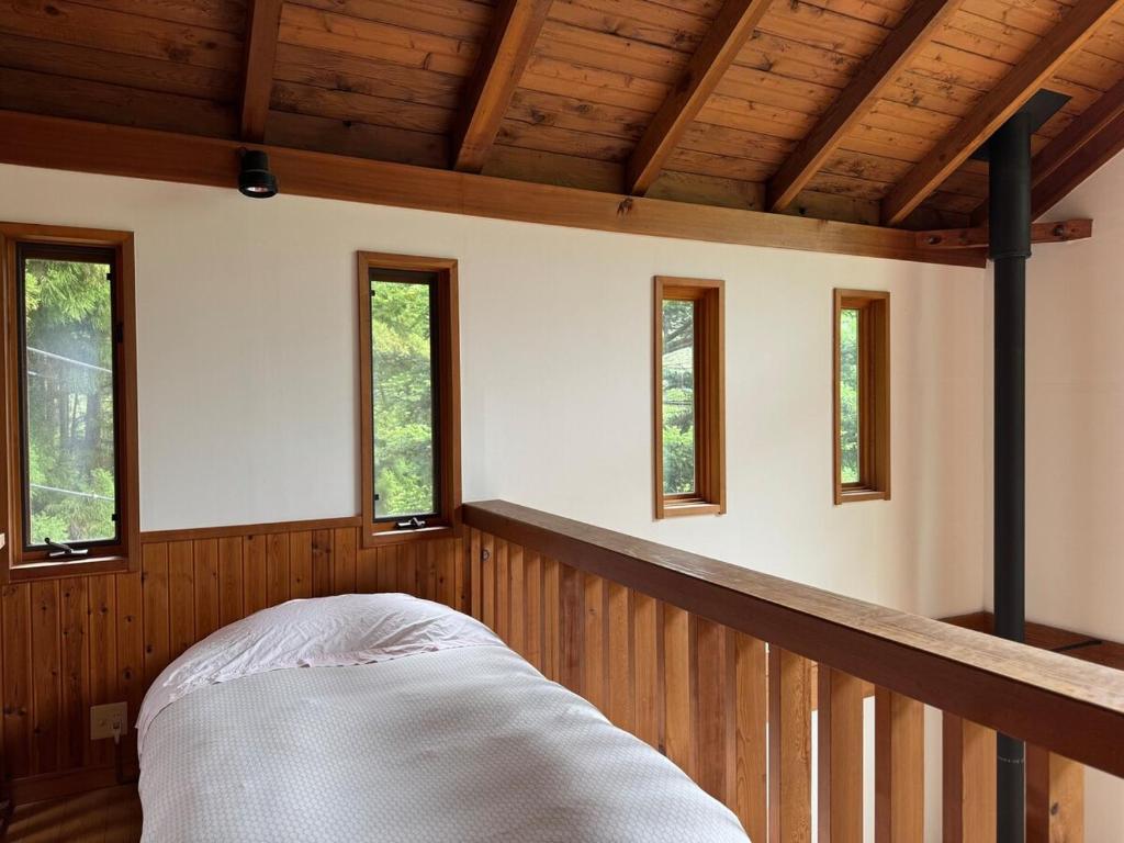 Cabin B vacation house rental Mt Fuji View 3 min lake Saiko 5min drive Lake Kawaguchi في فوجيكاواجوتشيكو: غرفة نوم بها سرير في غرفة بها نوافذ