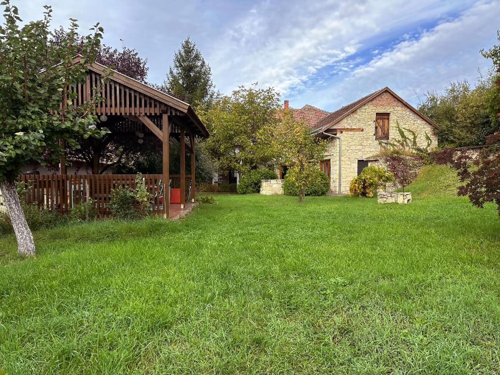 a house with a yard with a fence and green grass at Úrágya Vendégház in Mád