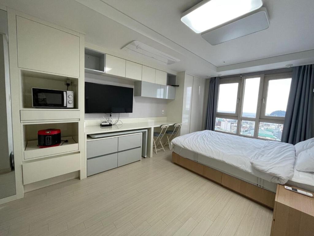 a bedroom with a bed and a desk with a tv at 트루엘 레지던스 in Seogwipo