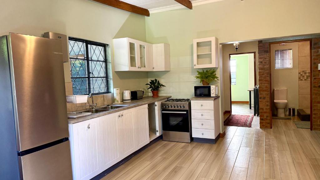 a kitchen with white cabinets and a stainless steel refrigerator at The Green Lantern - Howick in Howick