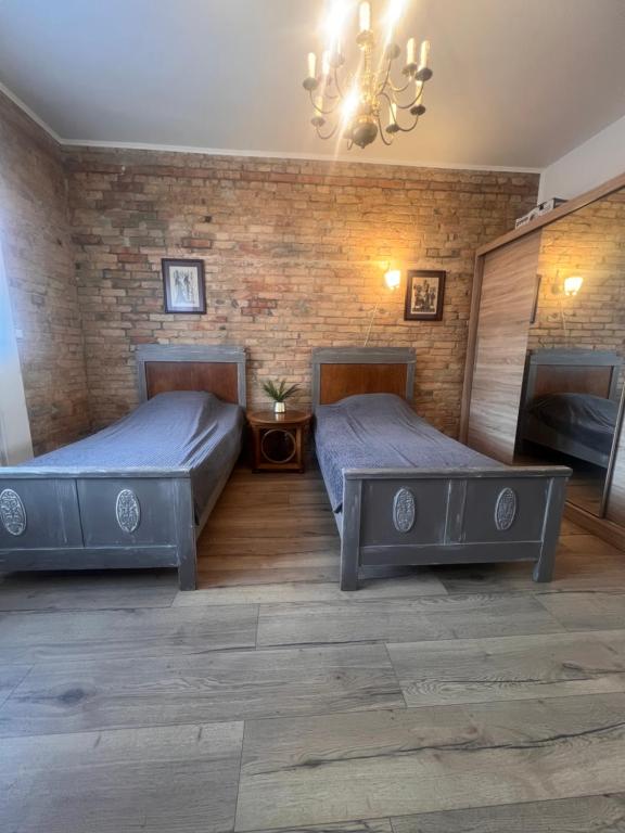 a bedroom with two beds and a brick wall at Louis Apartaments in Skorka