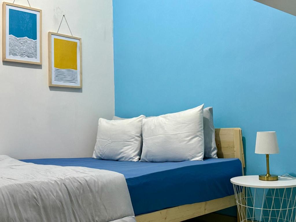 a bedroom with blue walls and a bed with pillows at Kalakoala by Zzz in Malang