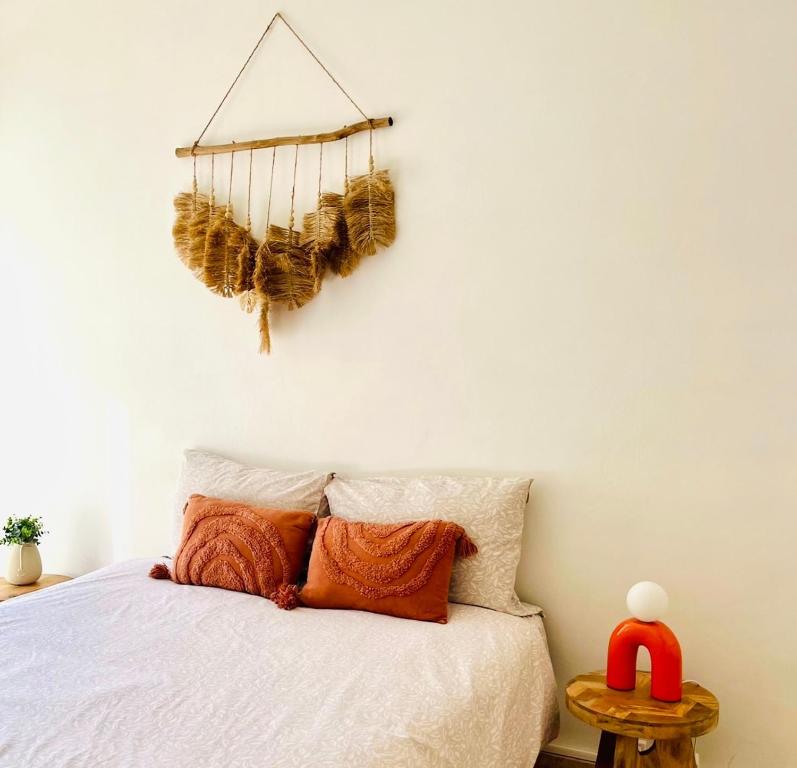 a bedroom with a white bed with a basket on the wall at Cocon jungle bohème 12 min de la mer in Martigues