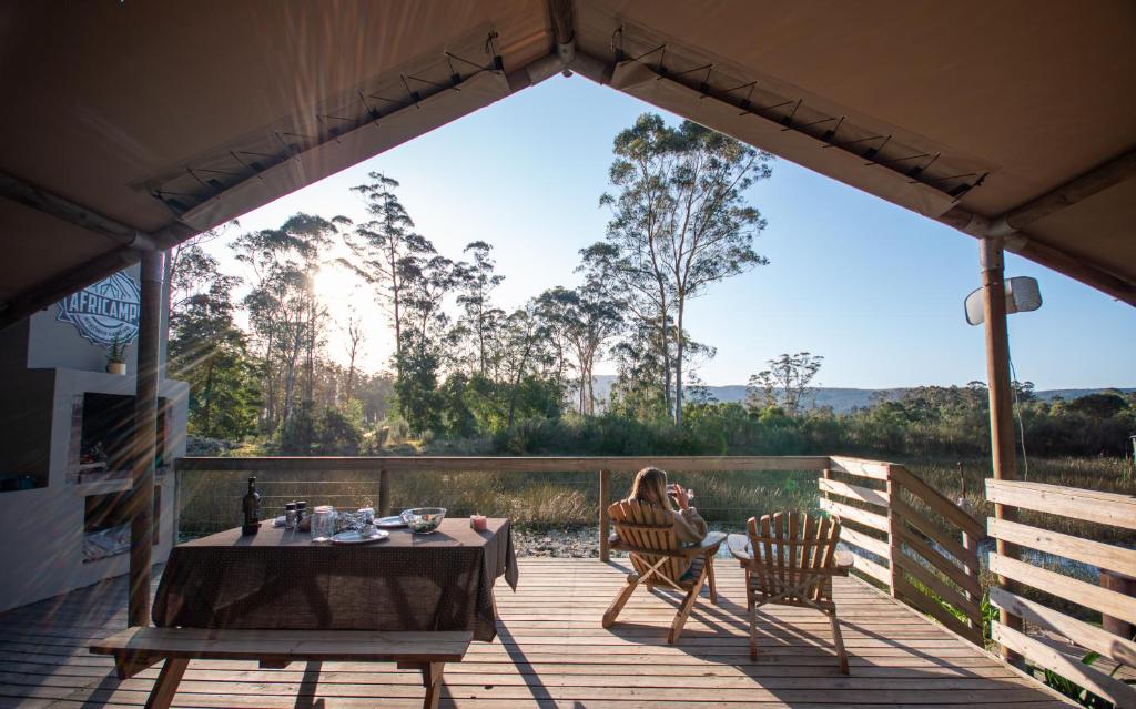 a table and chairs on a deck with a view at AfriCamps at Oakhurst in Wilderness