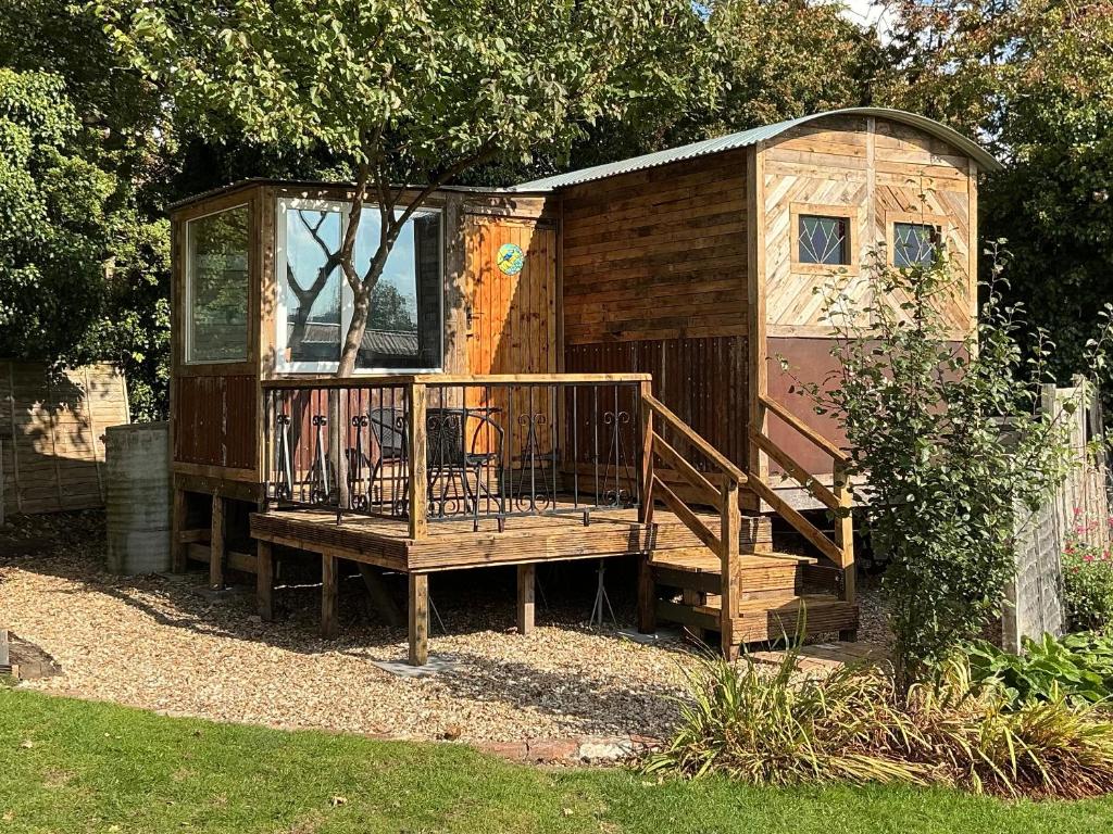 een houten hut met een veranda en een terras bij The Cosy Nest Hut in Keddington