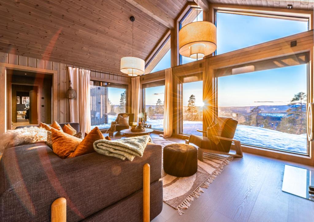 ein Wohnzimmer mit großen Fenstern und einem großen Sofa in der Unterkunft Luxurious Mountain Lodge in Ljørdal