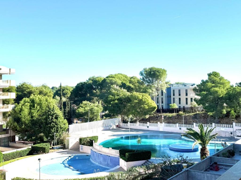 Blick auf einen Swimmingpool mit Bäumen und einem Gebäude in der Unterkunft Apartsalou Zen in Salou