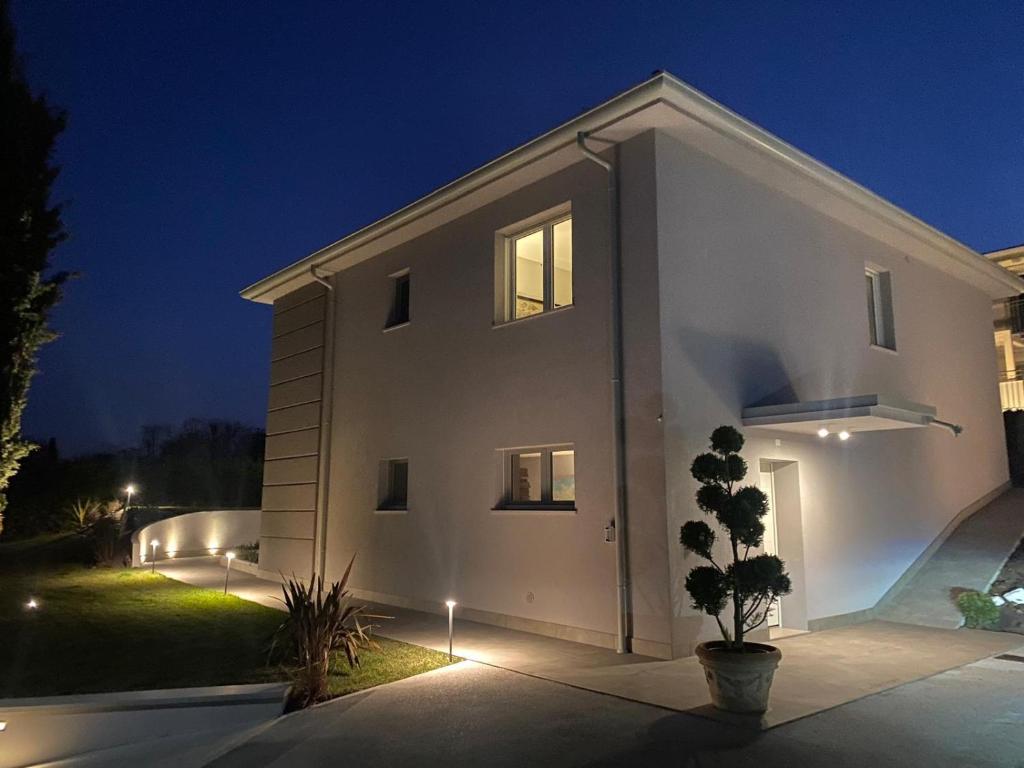 ein weißes Haus in der Nacht mit Lichtern in der Unterkunft Independent Room in Villa with Pool in Costermano sul garda