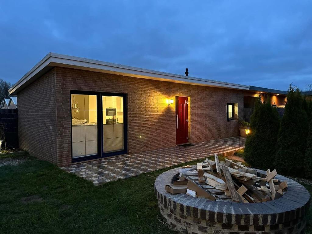 a brick house with a fire pit in front of it at Karolinas Deluxe Appartement-Bungalow in Dranske