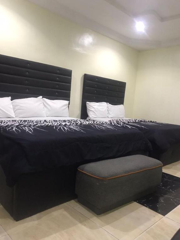 ein Schlafzimmer mit einem großen schwarzen Bett mit einer Bank in der Unterkunft Valley Point Hotel and Suites55 in Sangotedo