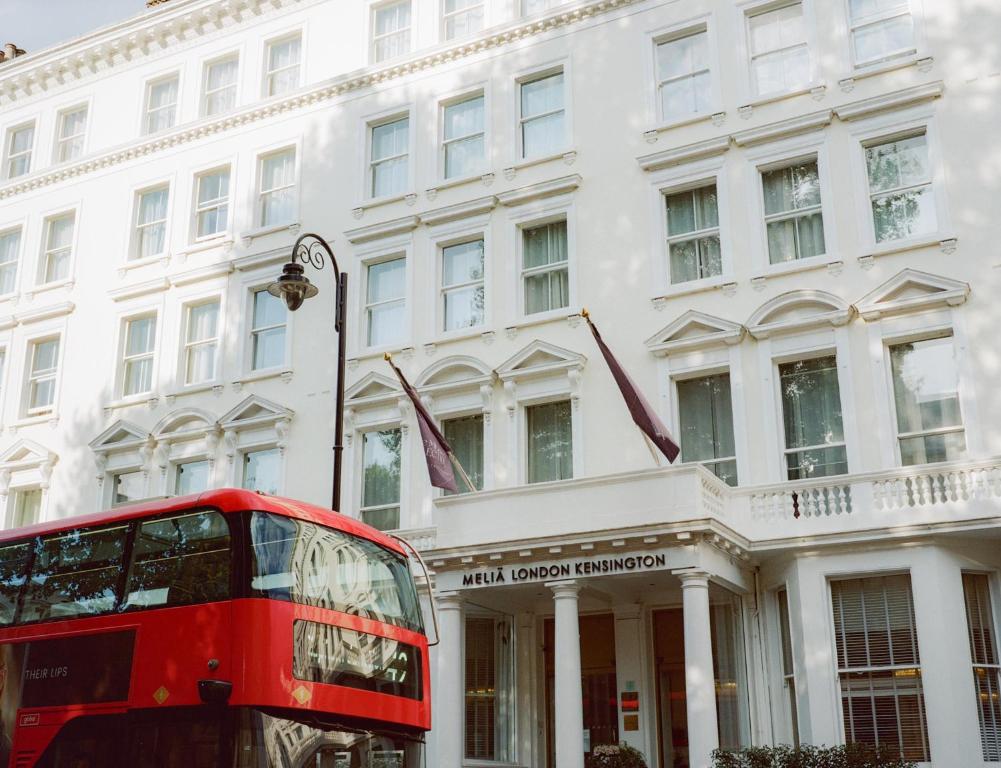 a red double decker bus parked in front of a building at Meliá London Kensington Member of Meliá Collection in London