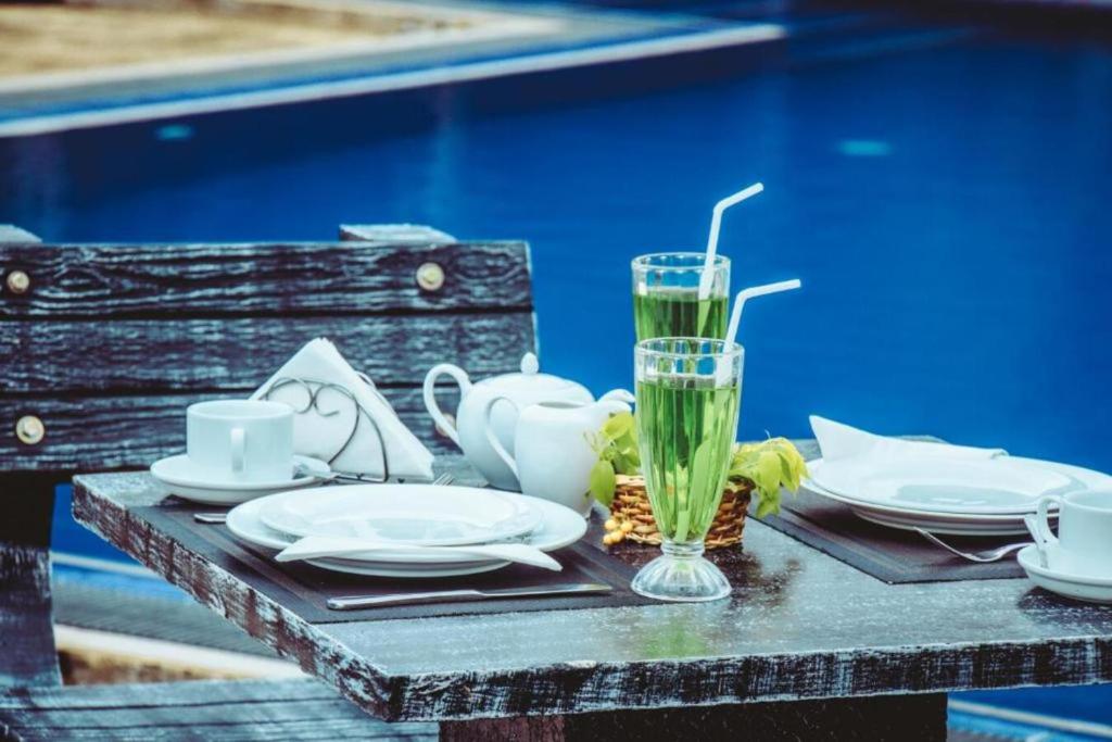 una mesa con platos y un vaso de agua. en Yala Aqu Hotel, en Kirinda