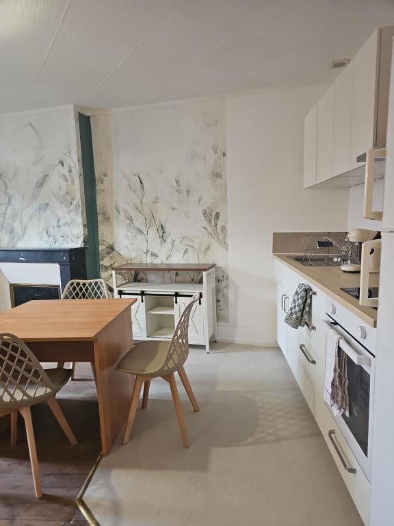 a white kitchen with a wooden table and chairs at Appartement coquet à la Machine in La Machine