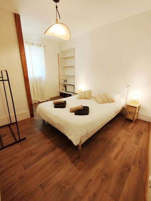a bedroom with a large white bed and wooden floors at Maison de charme au cœur d'Ax-Les-Thermes in Ax-les-Thermes