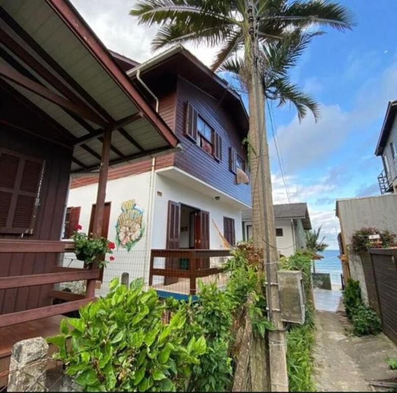 a house with a palm tree next to the ocean at Ar do Mar in Florianópolis