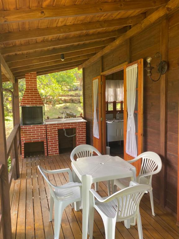 a porch with a table and chairs and a fireplace at CASA GAMBOA BEACH in Garopaba