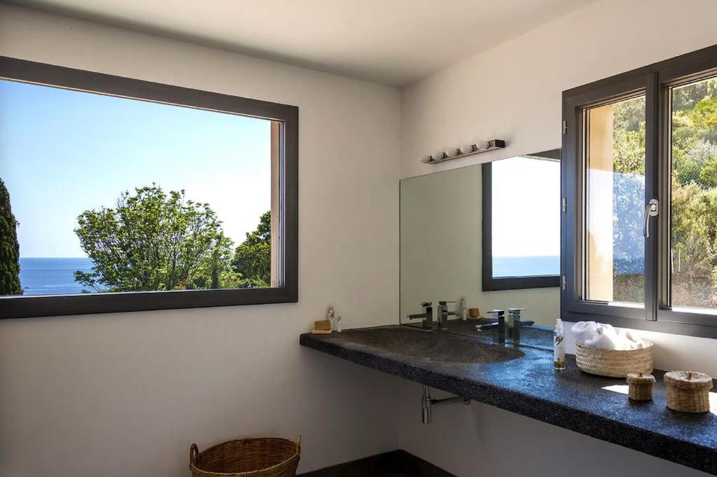 a bathroom with a sink and two windows at Villa 10 personnes avec piscine vue mer in Conca