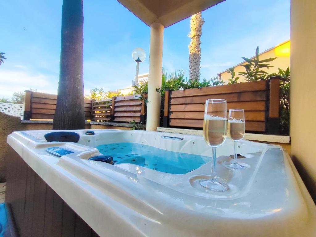 a hot tub with two glasses of wine at Villa 26, La Palmeraie au village naturiste in Cap d'Agde