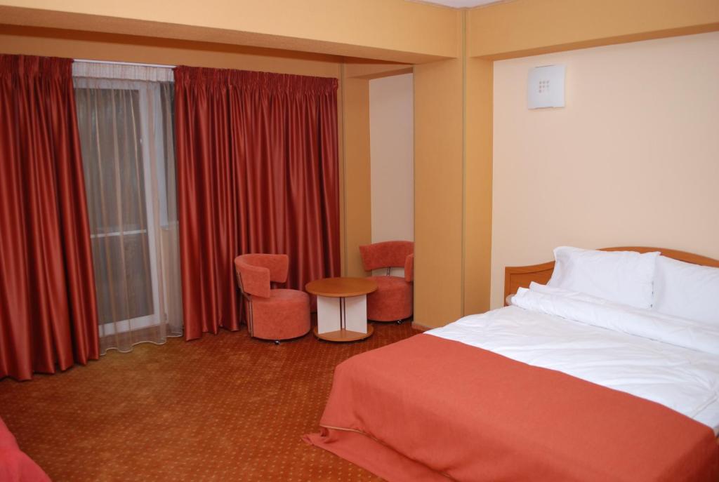 une chambre d'hôtel avec un lit, une table et des chaises dans l'établissement Hotel Migador, à Eforie Sud