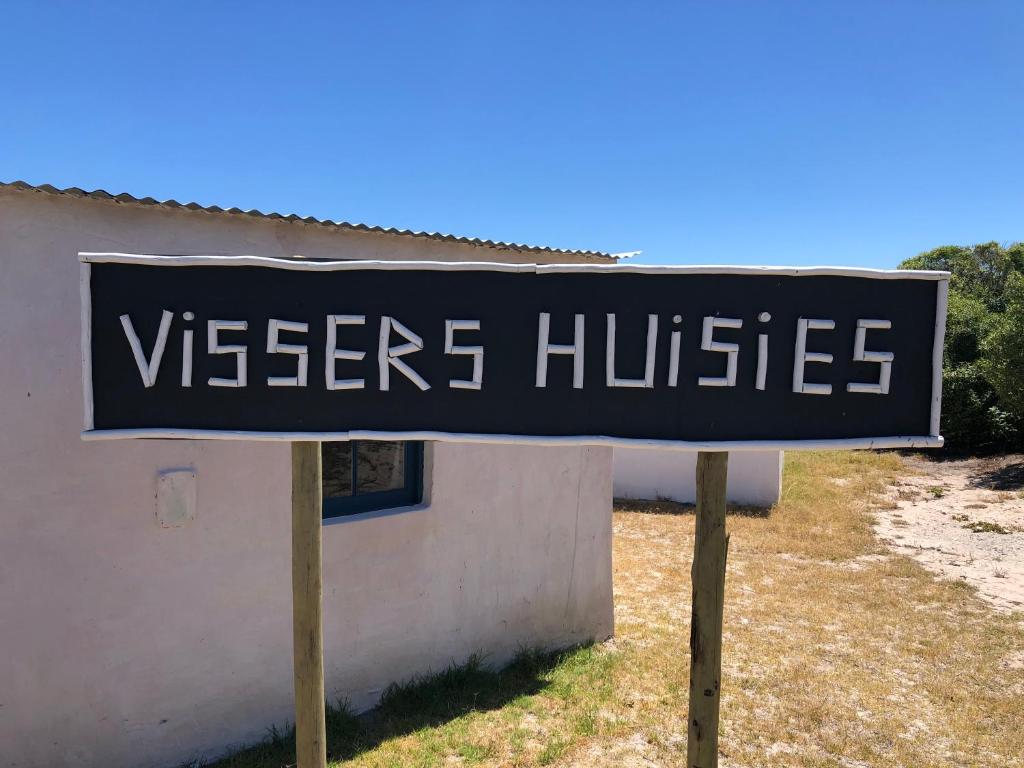 ein Schild vor einem weißen Gebäude in der Unterkunft VIssershuisies at Grootvlei Guest Farm 
