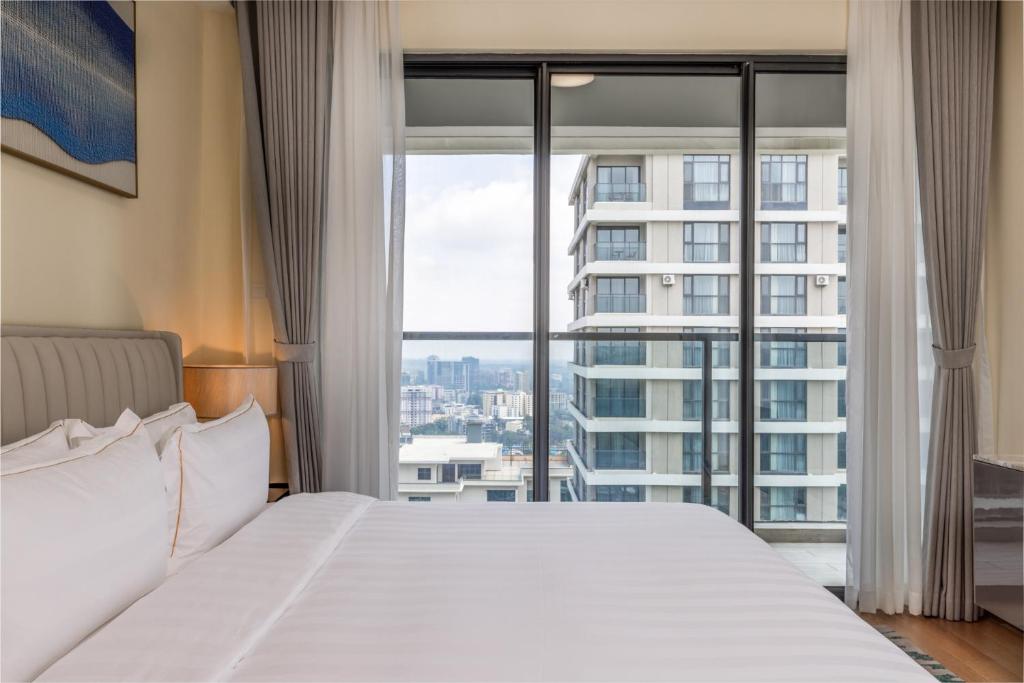 ein Schlafzimmer mit einem großen Bett und einem großen Fenster in der Unterkunft Pan Pacific Serviced Suites Nairobi in Nairobi