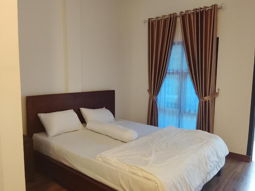 Bett mit weißer Bettwäsche und Kissen vor einem Fenster in der Unterkunft Pandava House Lombok in Lombok International Airport