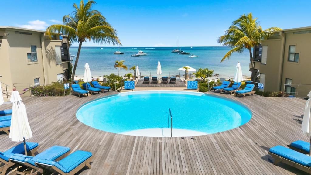 une piscine avec des chaises et l'océan en arrière-plan dans l'établissement Beachfront Le Cerisier Trou Aux Biches, Mon Choisy, à Mont Choisy