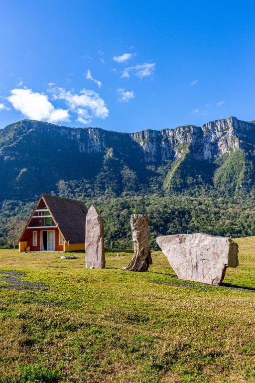 a house in a field with two large rocks at Chalé Refúgio Vô Chico in Alfredo Wagner