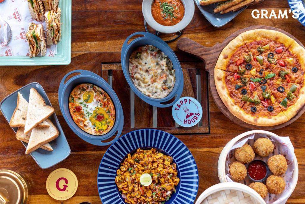 a wooden table topped with different dishes of food at Gram's at Shivom, Pawna Lake by StayVista in Lonavala
