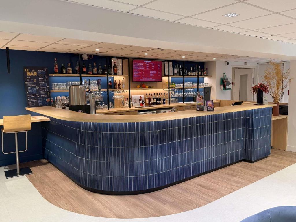 a bar in a store with a blue wall at ibis Rennes Beaulieu in Cesson-Sévigné