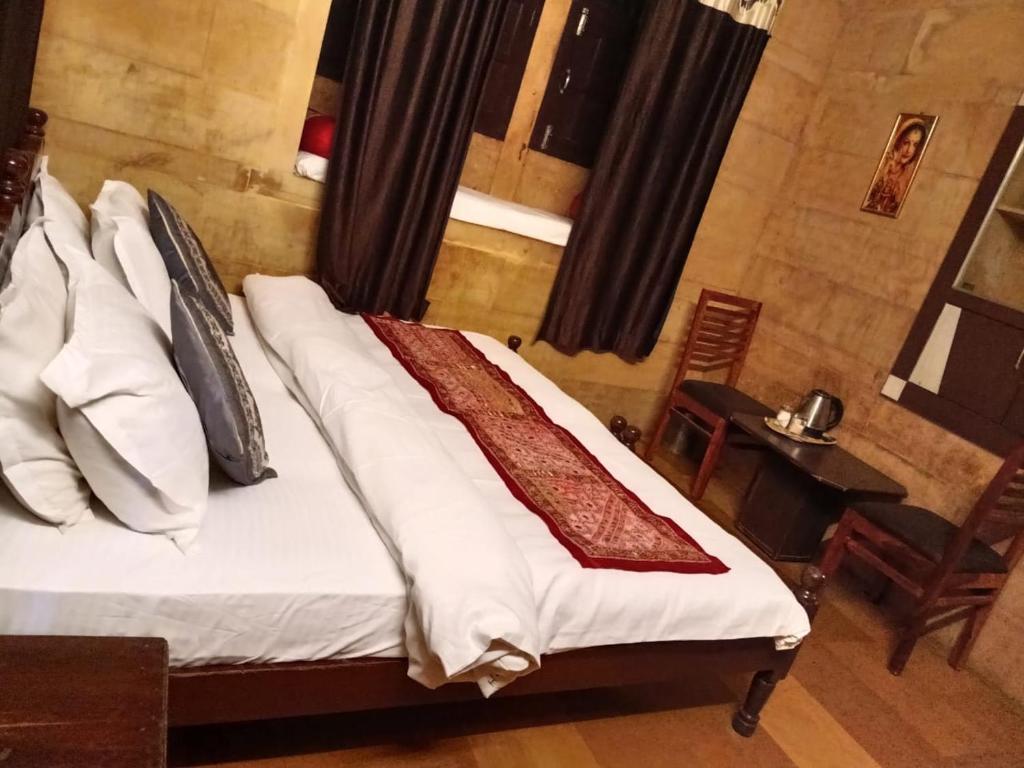 Hotel Al-raya Jaisalmer في جيلسامر: غرفة نوم بها سرير مع ملاءات ووسائد بيضاء