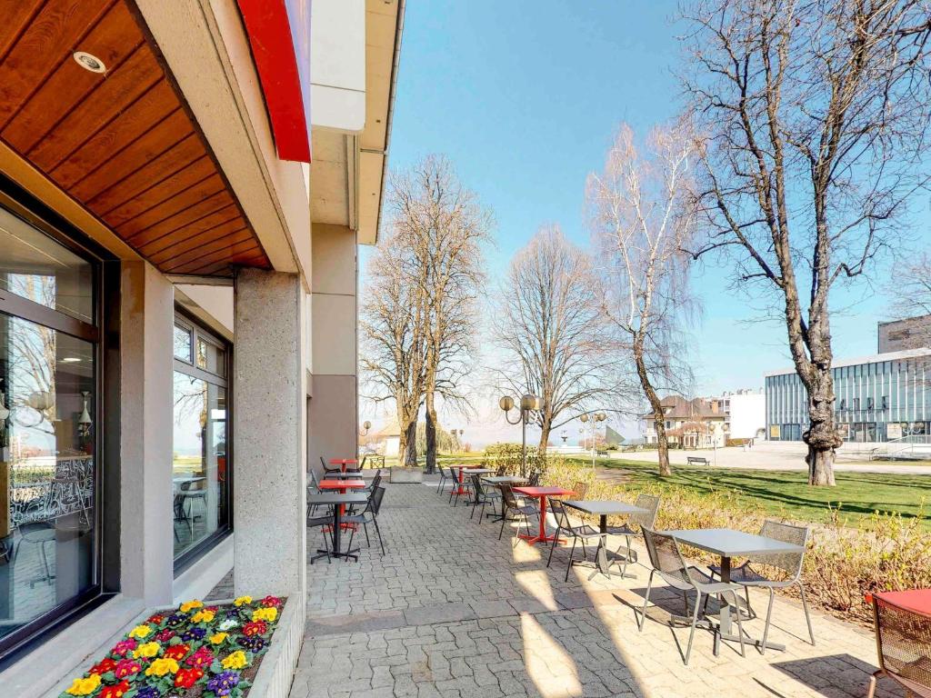 un patio avec des tables et des chaises à côté d'un bâtiment dans l'établissement ibis Thonon Centre, à Thonon-les-Bains