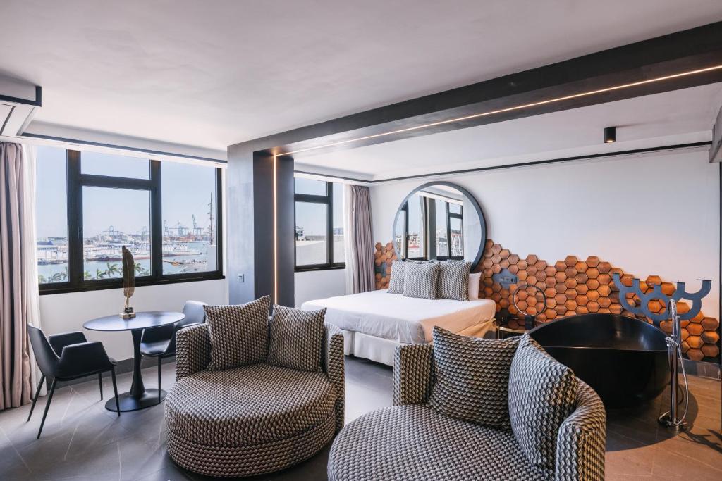 a hotel room with a bed and two chairs at Poem Suites by Airnest in Las Palmas de Gran Canaria