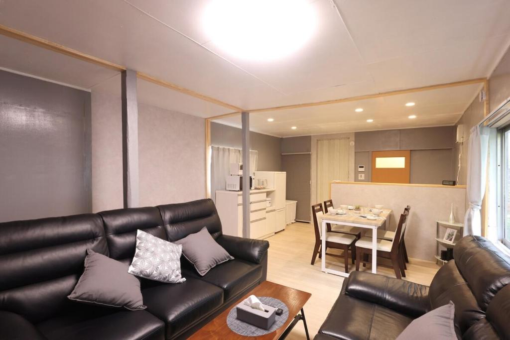 ein Wohnzimmer mit einer Ledercouch und einem Tisch in der Unterkunft くつろぎのお宿 やわや 駅北 in Toyama