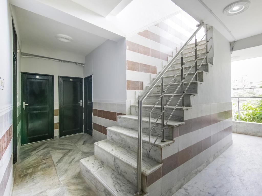 uma escadaria em um corredor com portas verdes em Hotel O Red Rose em Nova Deli