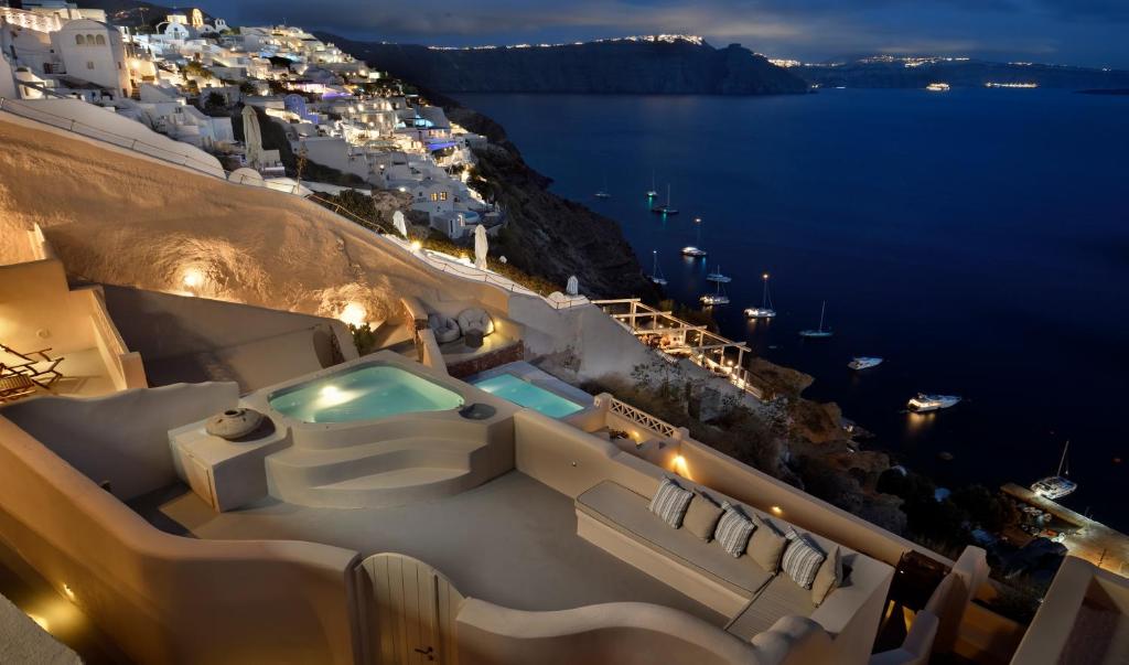 ein Pool an der Seite eines Gebäudes mit Blick auf das Meer in der Unterkunft THE A COLLECTION by K&K in Oia