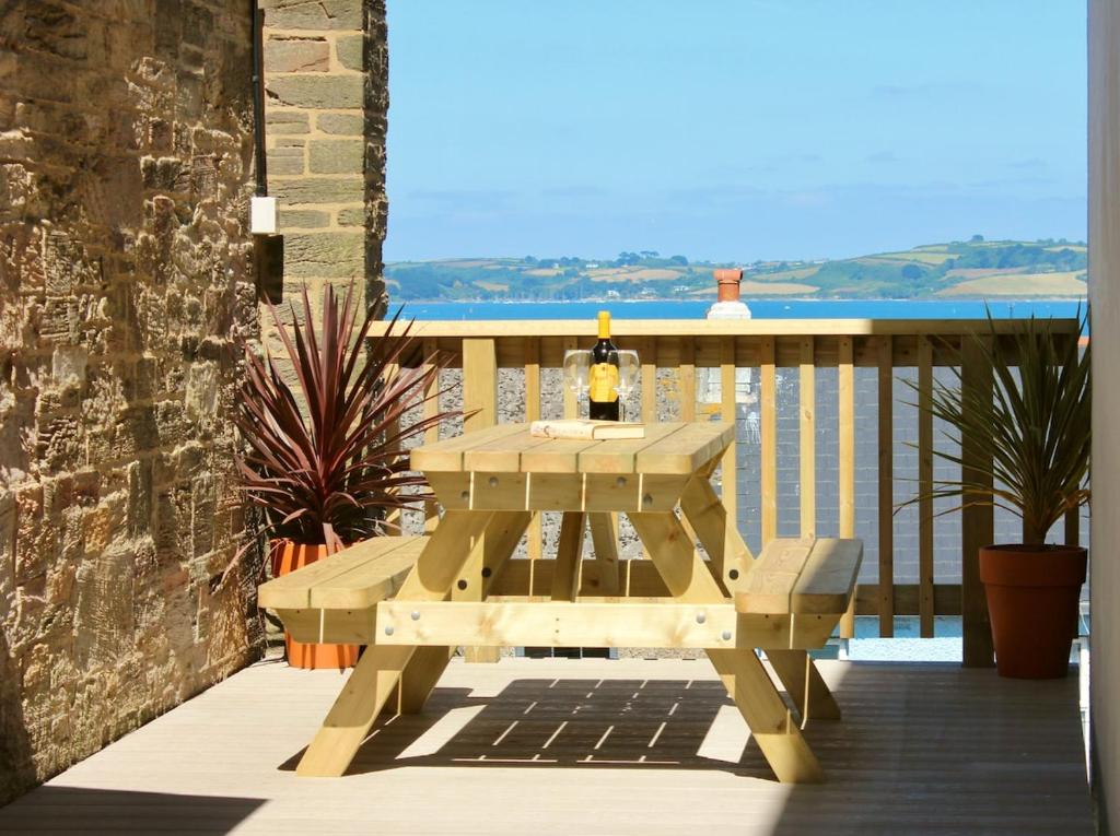 a picnic table on a balcony with a view of the ocean at The Quaker Hall - Private Deck - Stunning Views in Falmouth